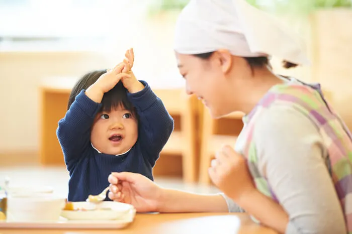 保育士が園児にご飯を食べさせる様子