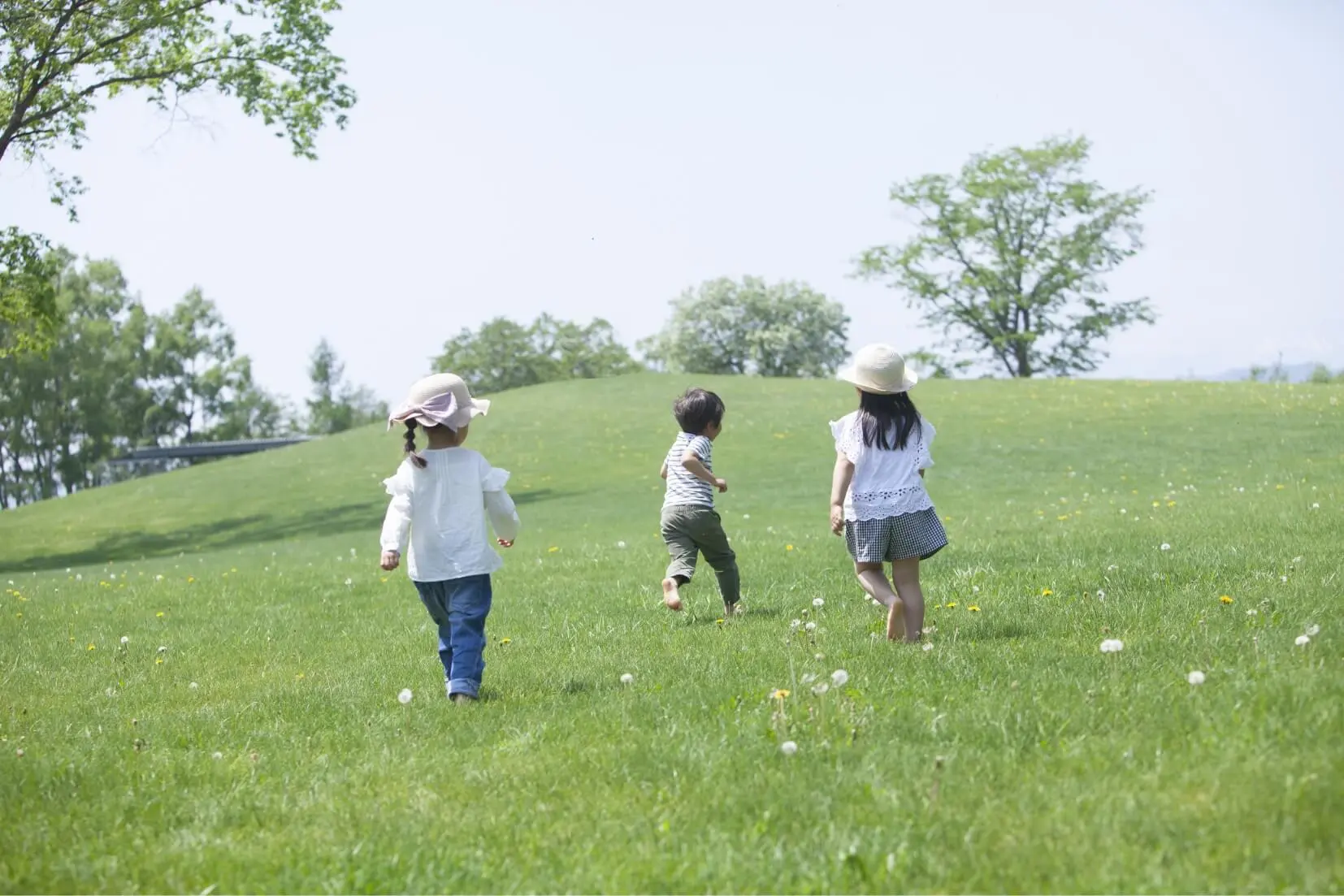 野原で走る３人の子どもたちの様子